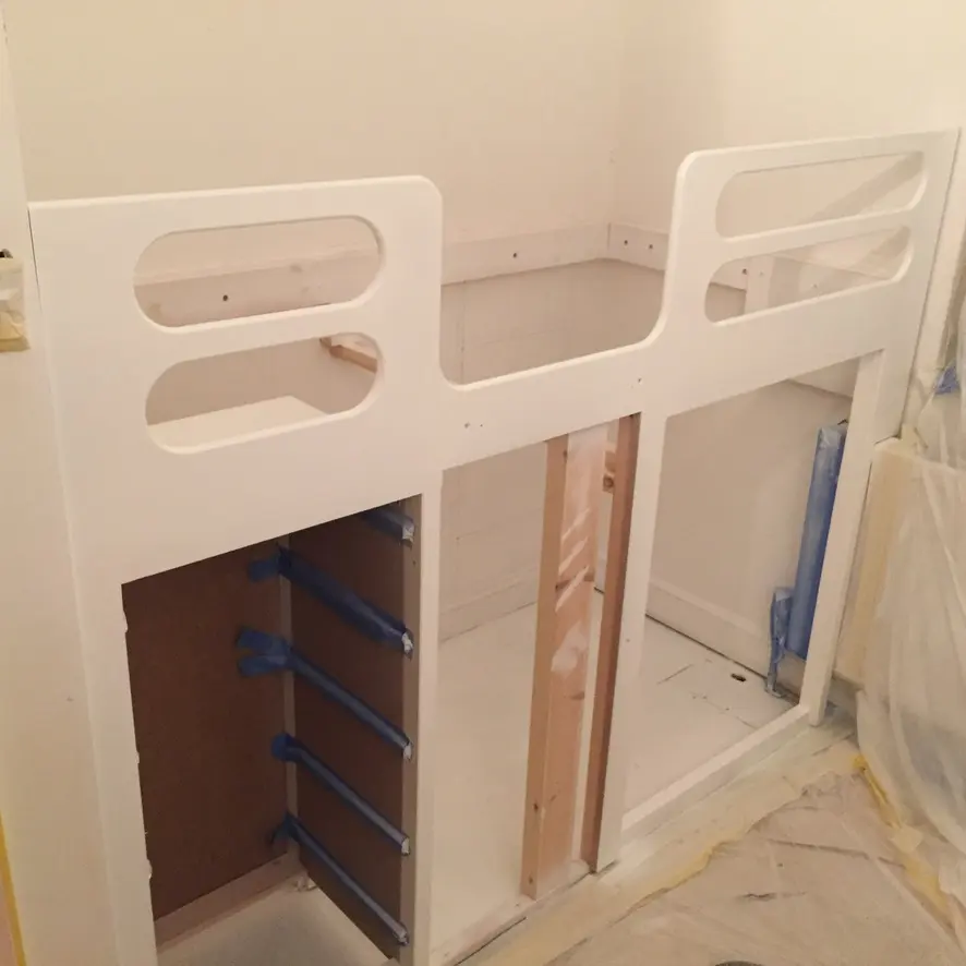 White painted step shelving unit in a dust-sheeted room