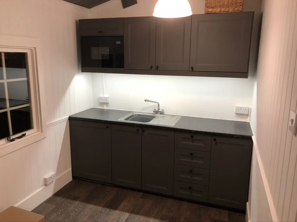 Howdens dark grey shaker in a garden cabin: sink run, drawers and a built-in microwave