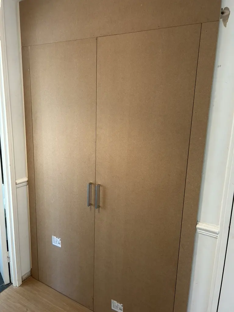 Closed MDF utility cupboard with two tall doors and handles