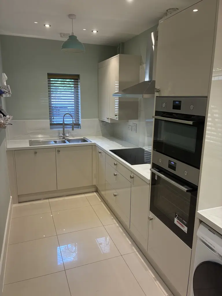 Cream gloss L-shaped kitchen with double ovens