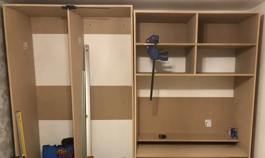 Raw MDF wardrobe and shelving carcasses being built into a bedroom wall